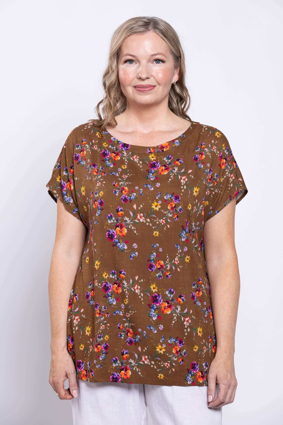 Woman wearing a brown floral linen tee with dolman cap sleeves, closeup view