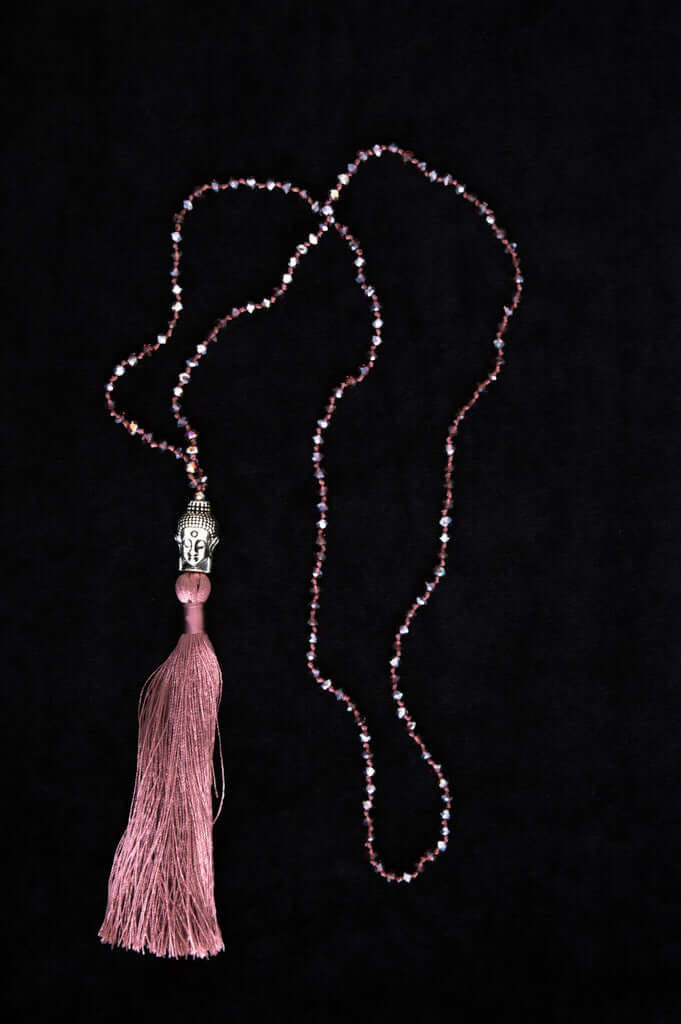 Pink beaded mala necklace with Buddha head charm and tassel on black background