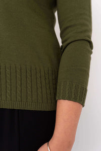 Close-up of cable knit detailing on the hem and cuff of an olive green sweater