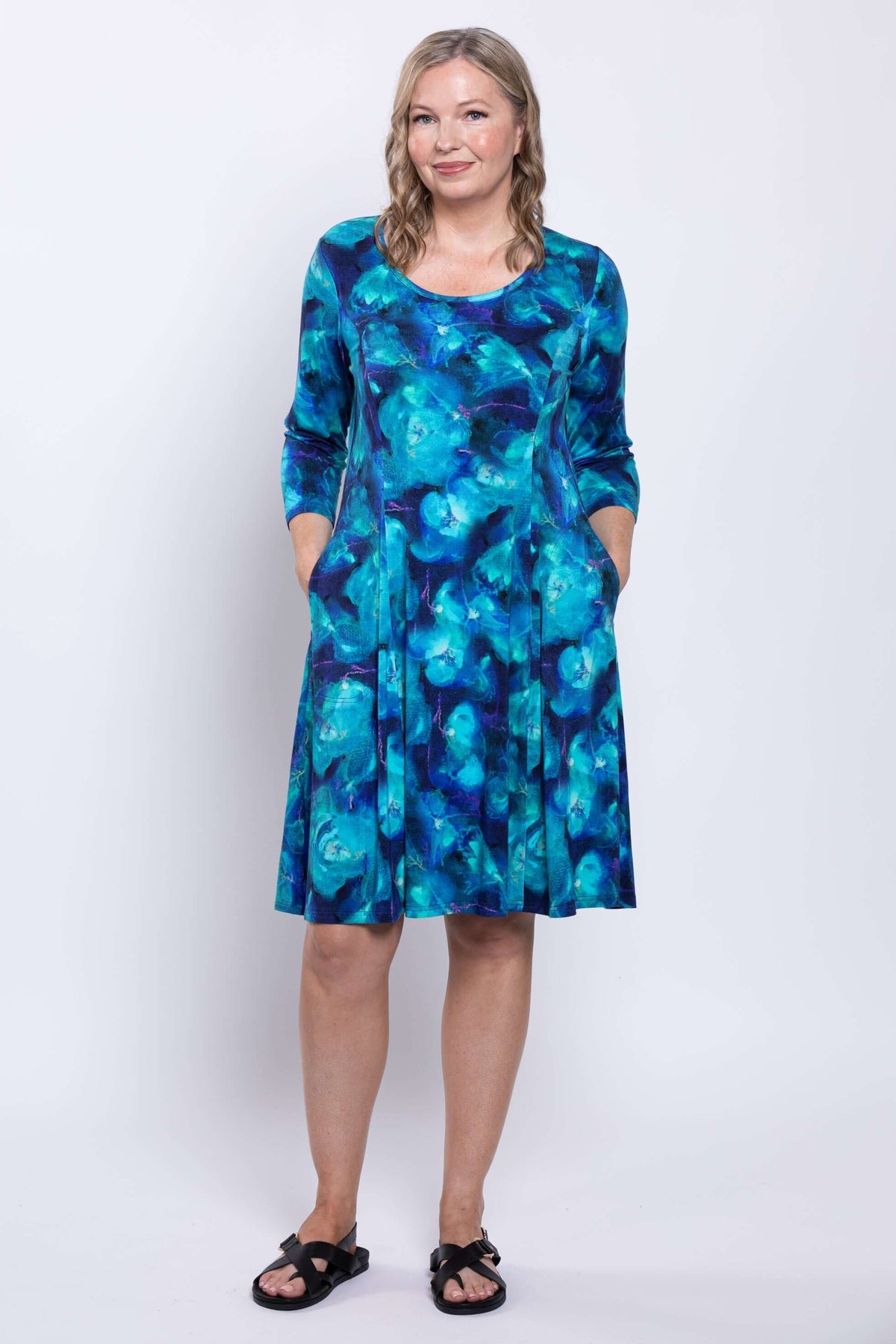 Woman standing hands in pockets, modeling Callie blue A-line dress with abstract print