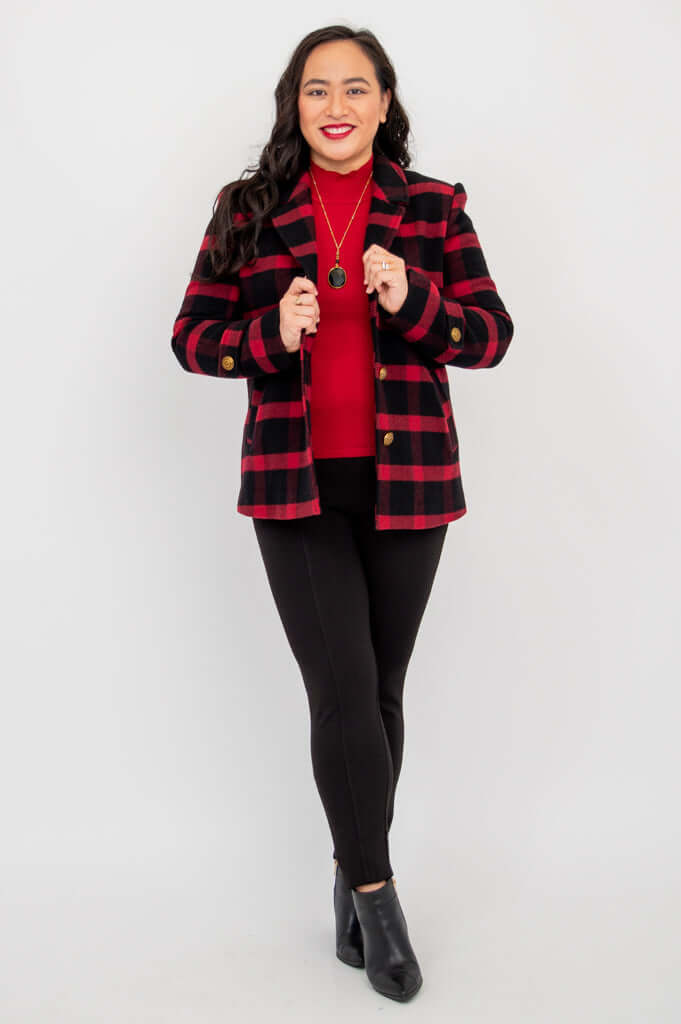 Woman wearing red and black plaid blazer with arms crossed in front