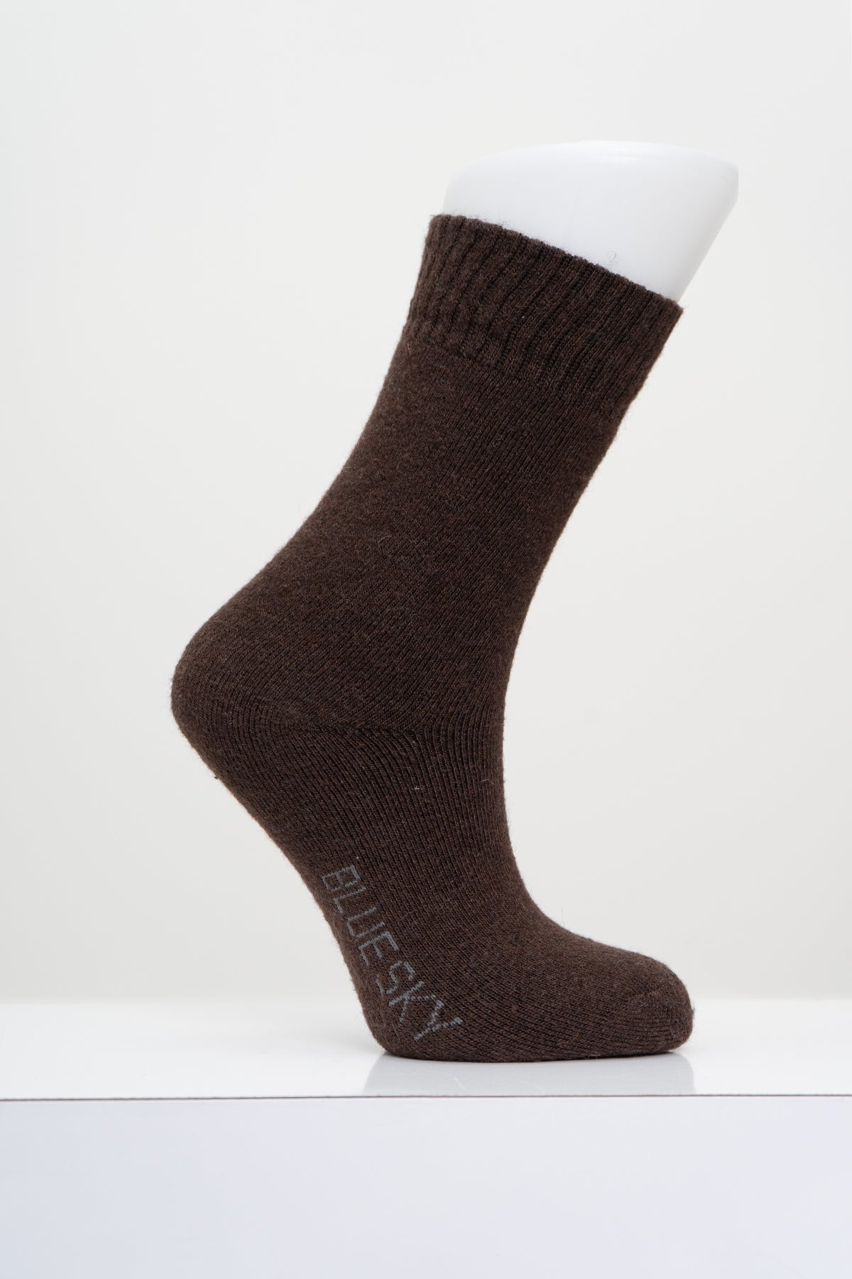 A single dark brown knit sock displayed on a white mannequin foot against a clean white background. 