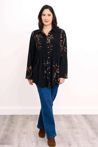 Woman walking forward in black floral smocked tunic shirt, blue jeans, brown boots