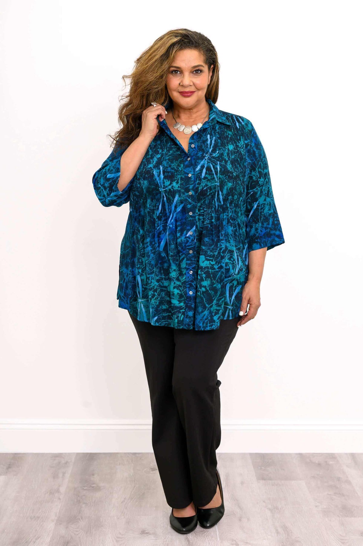 Model holding collar while wearing the Cindy blue lagoon patterned smocked top