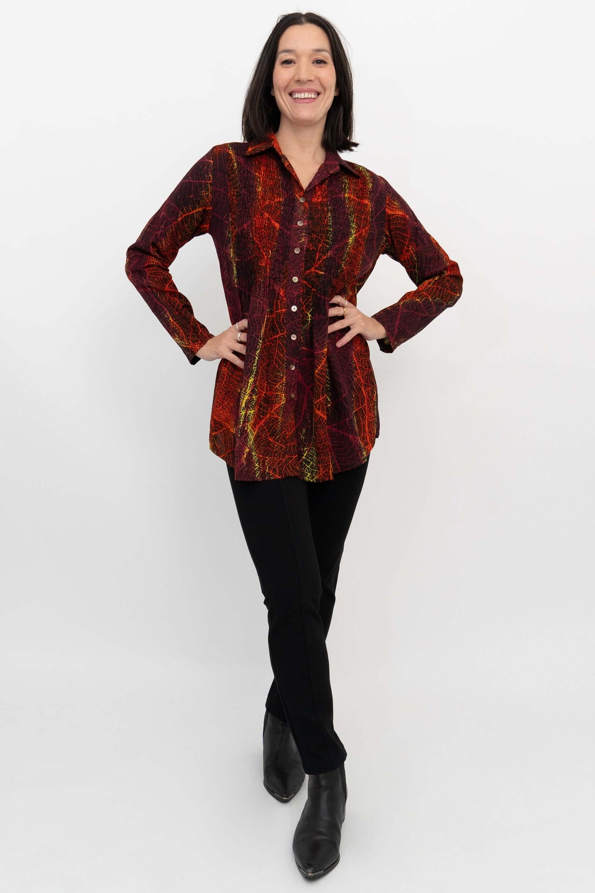 Woman posing in a vibrant, long sleeve smocked tunic top with hands on hips