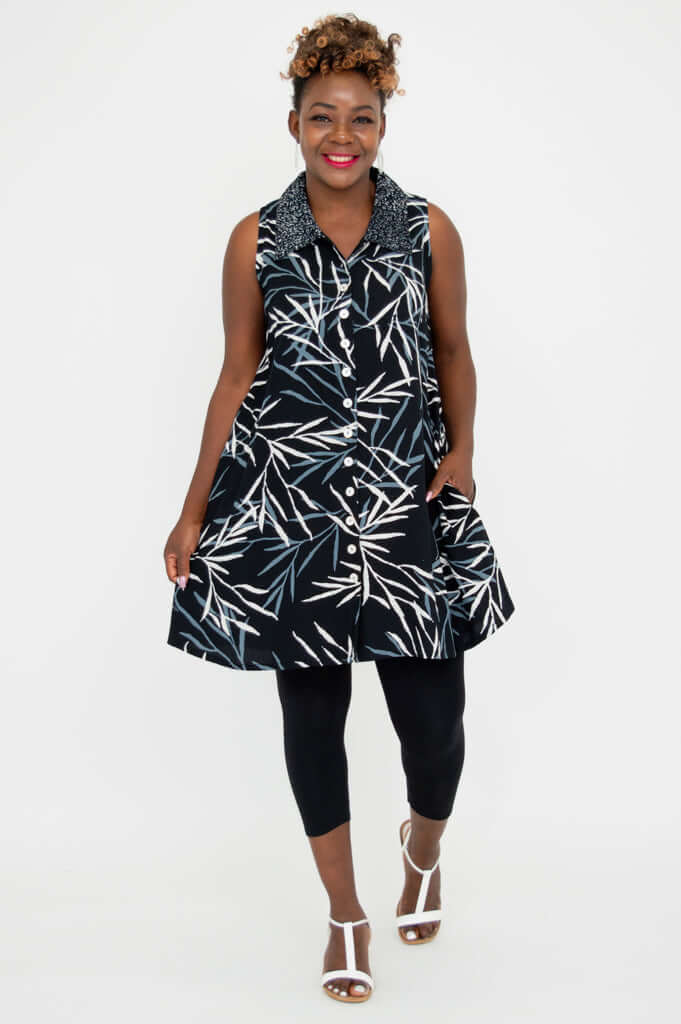 Model smiling in Cissy Tank, a black sleeveless button up tunic with white and blue print