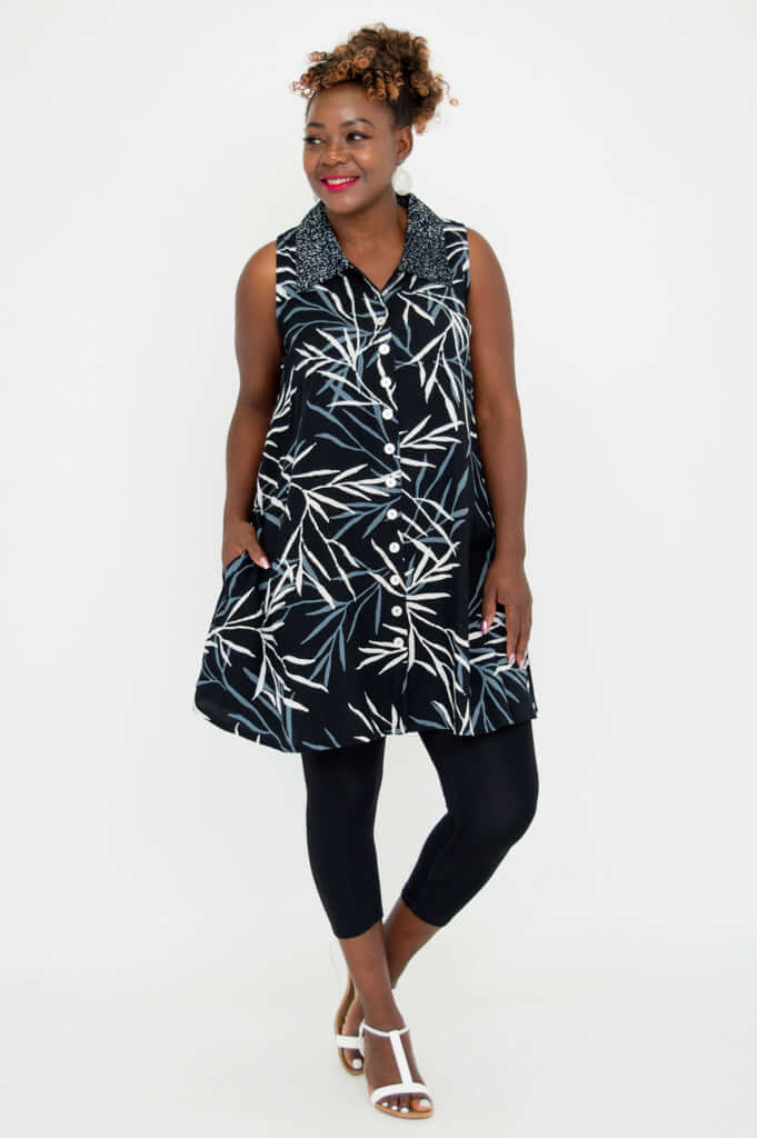Model posing sideways in A-line black tank top with leaf print and white buttons
