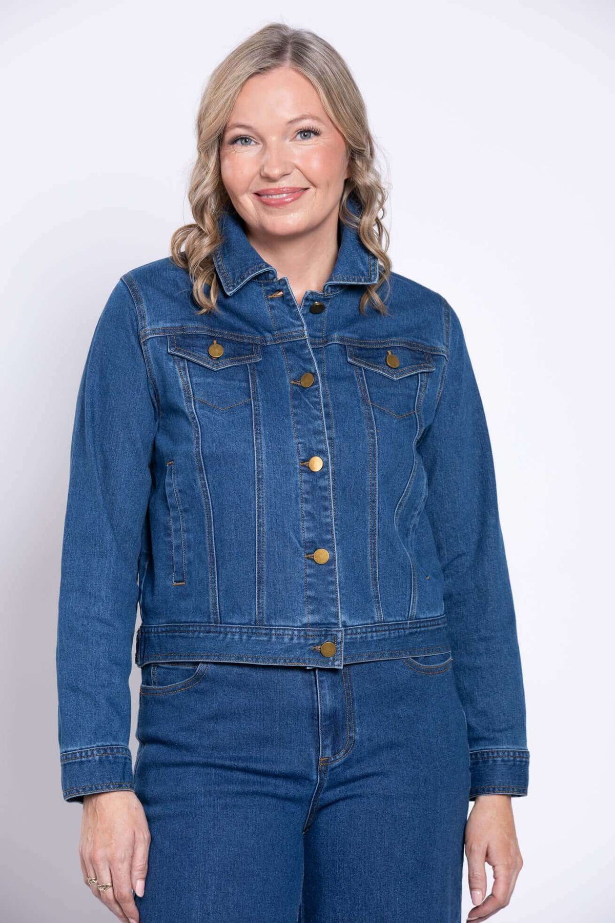 Woman wearing a classic blue denim jean jacket, front view, smiling