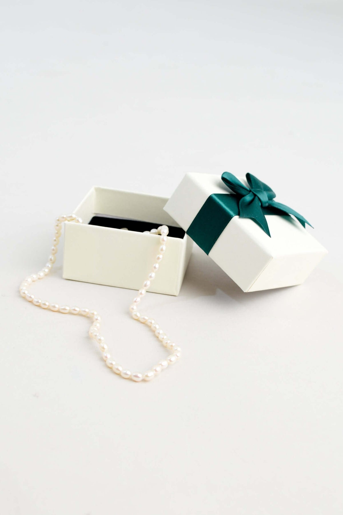Classic pearl necklace presented in an open cream gift box with green ribbon