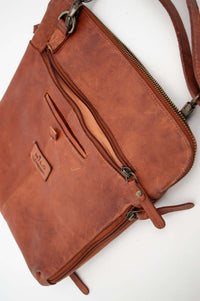 Close-up of leather bag showing exterior zip pocket and branded patch