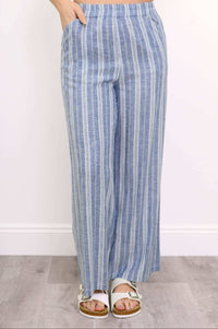 Close-up front view of woman wearing white sandals and ankle-length blue striped pants