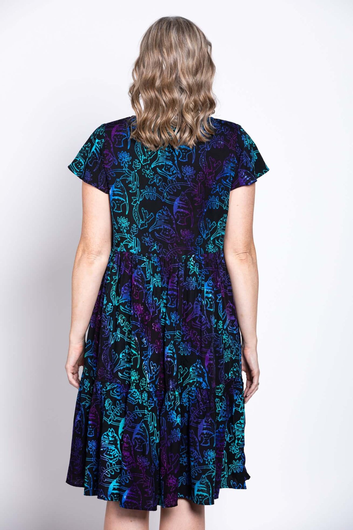 Close-up back view of a woman wearing a black dress with blue and purple botanical print