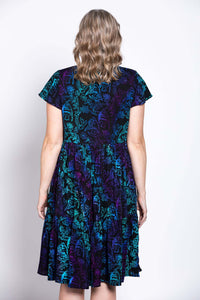 Close-up back view of a woman wearing a black dress with blue and purple botanical print