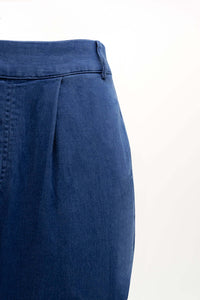 Close-up of blue pants showing pleated front and waistband detail
