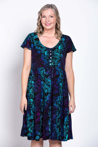 Close-up of a woman in a tiered black dress with blue and purple botanical print, front view