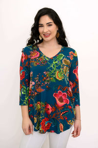 Close-up front view of woman wearing gold leaf earrings and multicolor v-neck floral print top