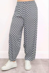 Close-up of black and white gingham barrel-leg pants with elastic waistband and sneakers