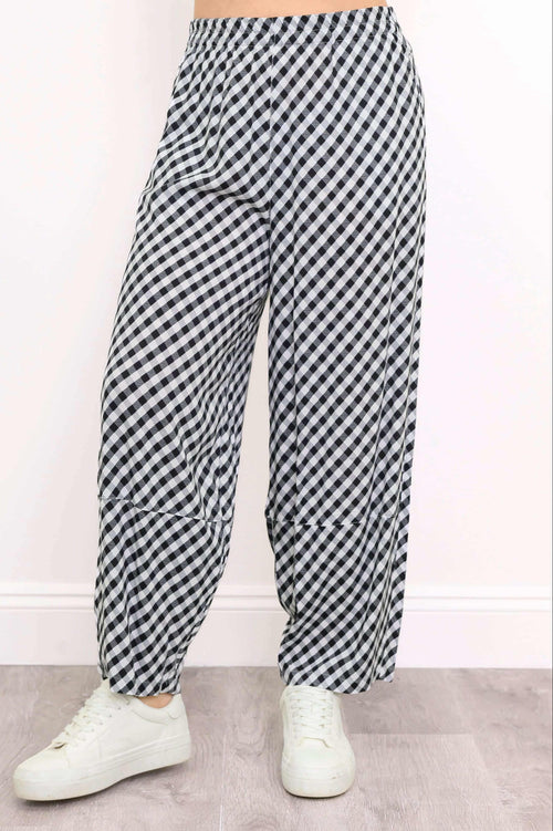 Close-up of black and white gingham barrel-leg pants with elastic waistband and sneakers
