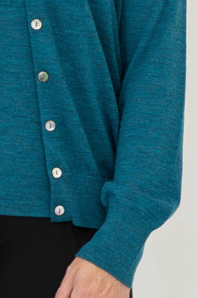 Detailed view of the button front closure and knit texture on a soft teal blue-green sweater.
