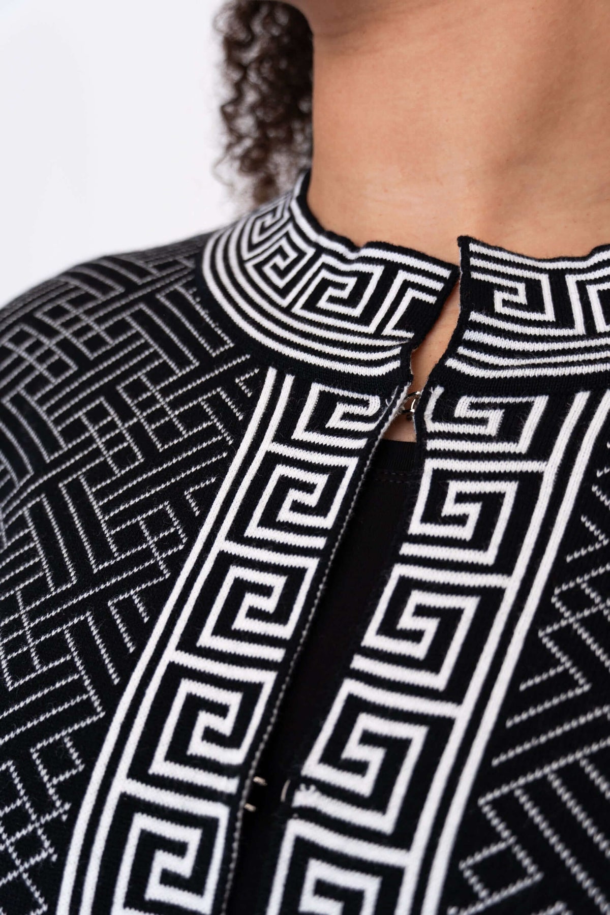 Close-up of the mandarin neck and front trim on a black and white geometric cardigan