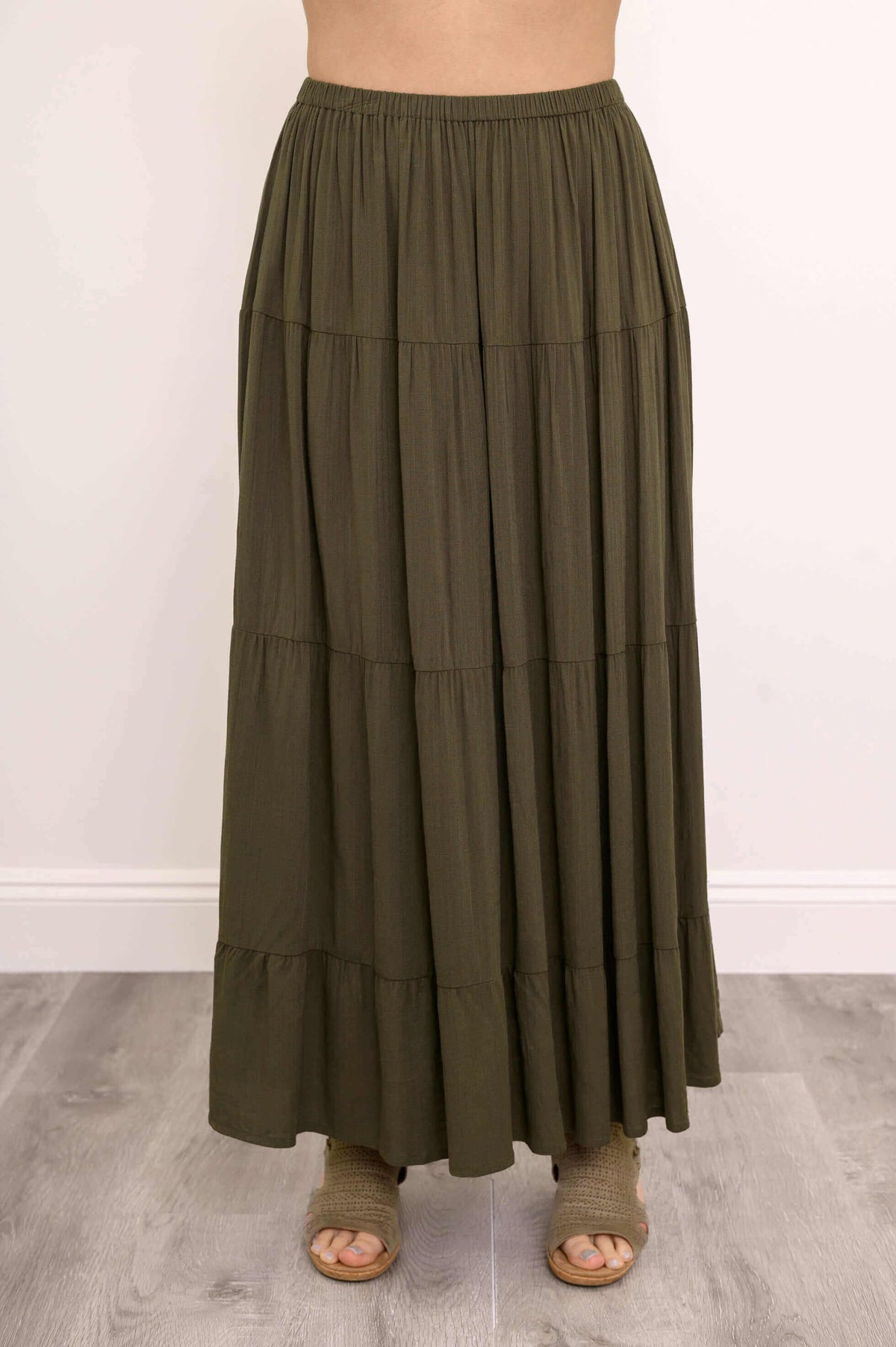 Close-up of olive green tiered maxi skirt focusing on elastic waistband and gathered tiers