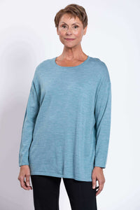 Short-haired woman modeling a light blue Merino wool pullover, close-up