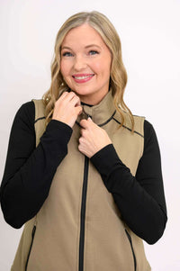 Close-up of woman smiling and zipping tan Hartford Utility Vest