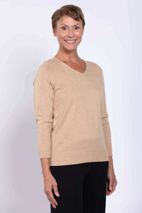 Close-up of woman wearing beige V-neck cotton sweater and black pants