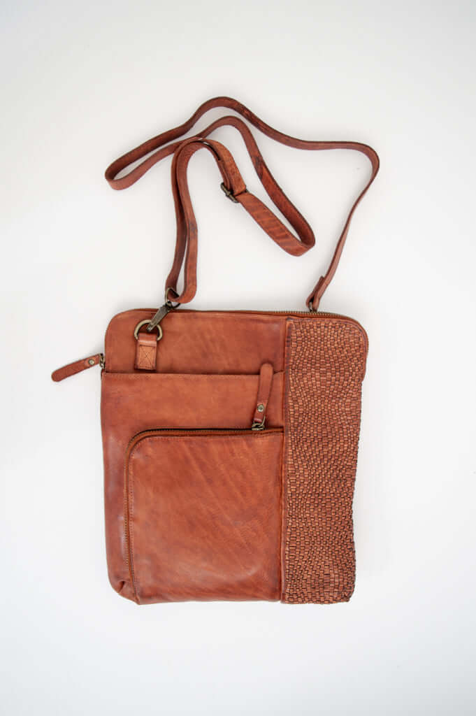 Full view of a cognac leather crossbody bag with woven side detail and adjustable strap