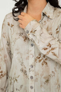 Close-up of blouse collar and button cuff on beige floral button-up shirt