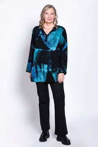 Woman standing in a black and blue Batik blouse, black pants, and black boots against a white background