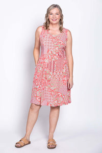 Woman in coral floral print sleeveless dress, standing with one leg forward, front view