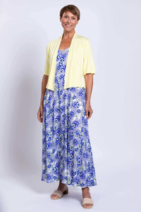 Woman layering the blue and white maxi dress with a short sleeve yellow cardigan