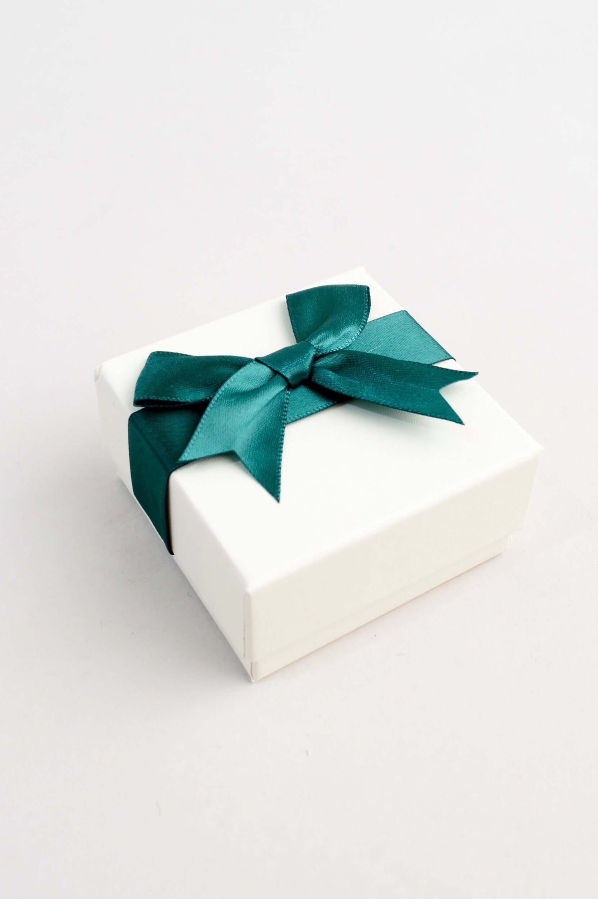 Closed cream gift box tied with a dark green satin ribbon bow