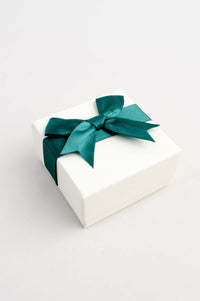 Closed cream gift box tied with a dark green satin ribbon bow