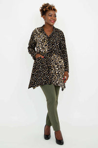 Model crossing legs in Laney Blouse – Black Gold Abstract