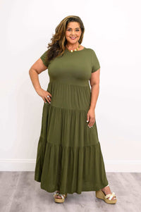 Curvy woman posing in olive green tiered maxi dress with a statement necklace