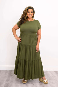 Curvy model in tiered olive maxi dress with gold necklace and wedge sandals