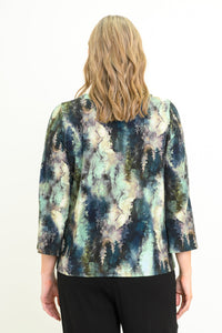 Back view of a women's green leaf patterned long-sleeve bamboo top styled with black pants.