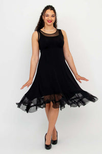 Model twirling in black sleeveless dress with mesh hem and layered look