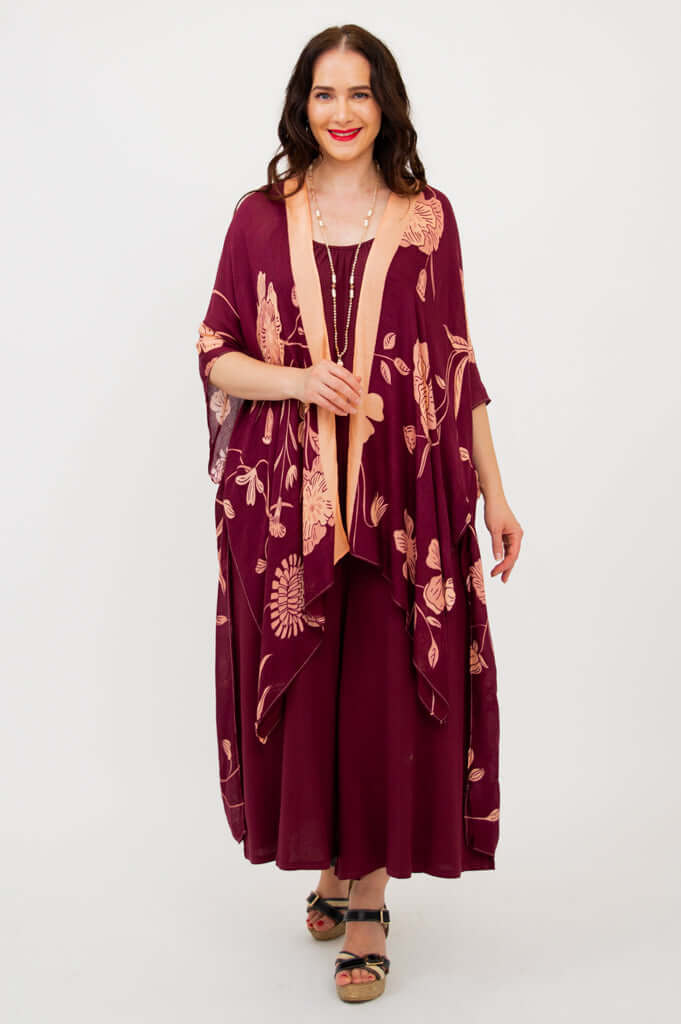 Woman in burgundy kimono wrap with peach floral design, hands at sides