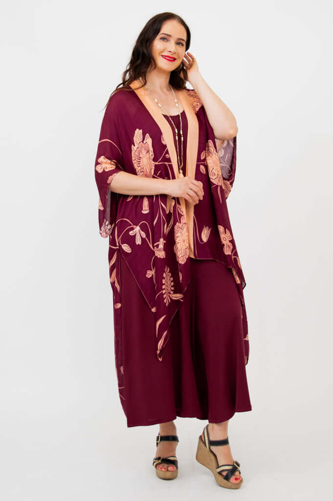 Woman smiling in burgundy floral kimono wrap, hand touching hair