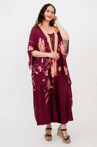 Woman smiling in burgundy floral kimono wrap, hand touching hair