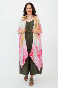 Woman wearing Darcy kimono wrap with pink and gold floral design over olive jumpsuit