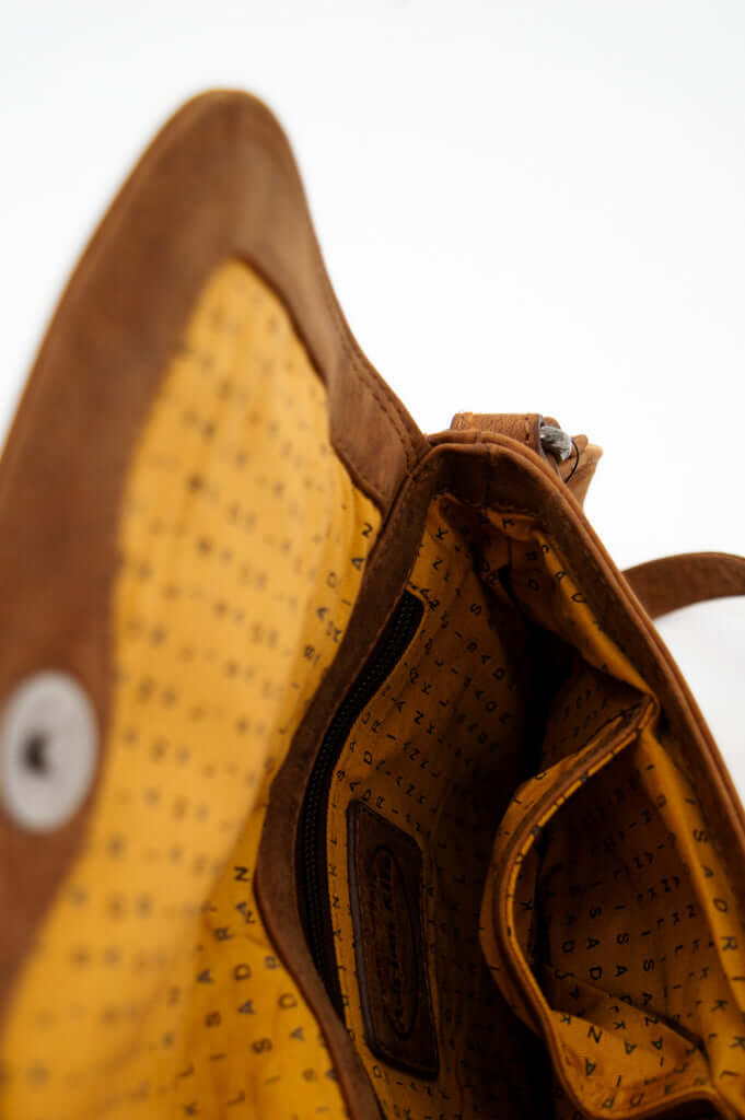 Deep interior shot of crossbody bag revealing pocket details and yellow lining