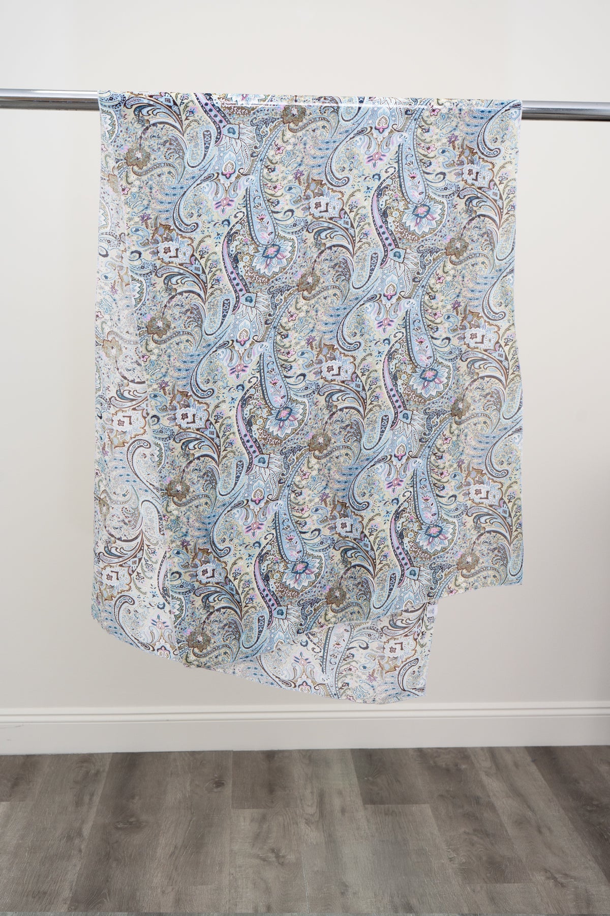 A large silk scarf with a blue, pink, and green paisley pattern displayed on a metal rod against a white background, front view