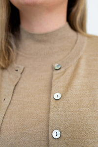 Close up of tan merino wool sweater fabric and cardigan buttons