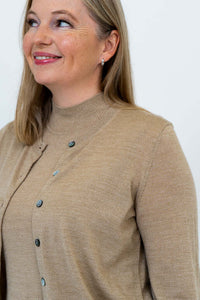 Detail of neckline and upper chest showing beige cardigan and button accents