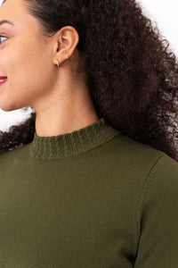 Close-up of the cable knit mock neckline on an olive green sweater