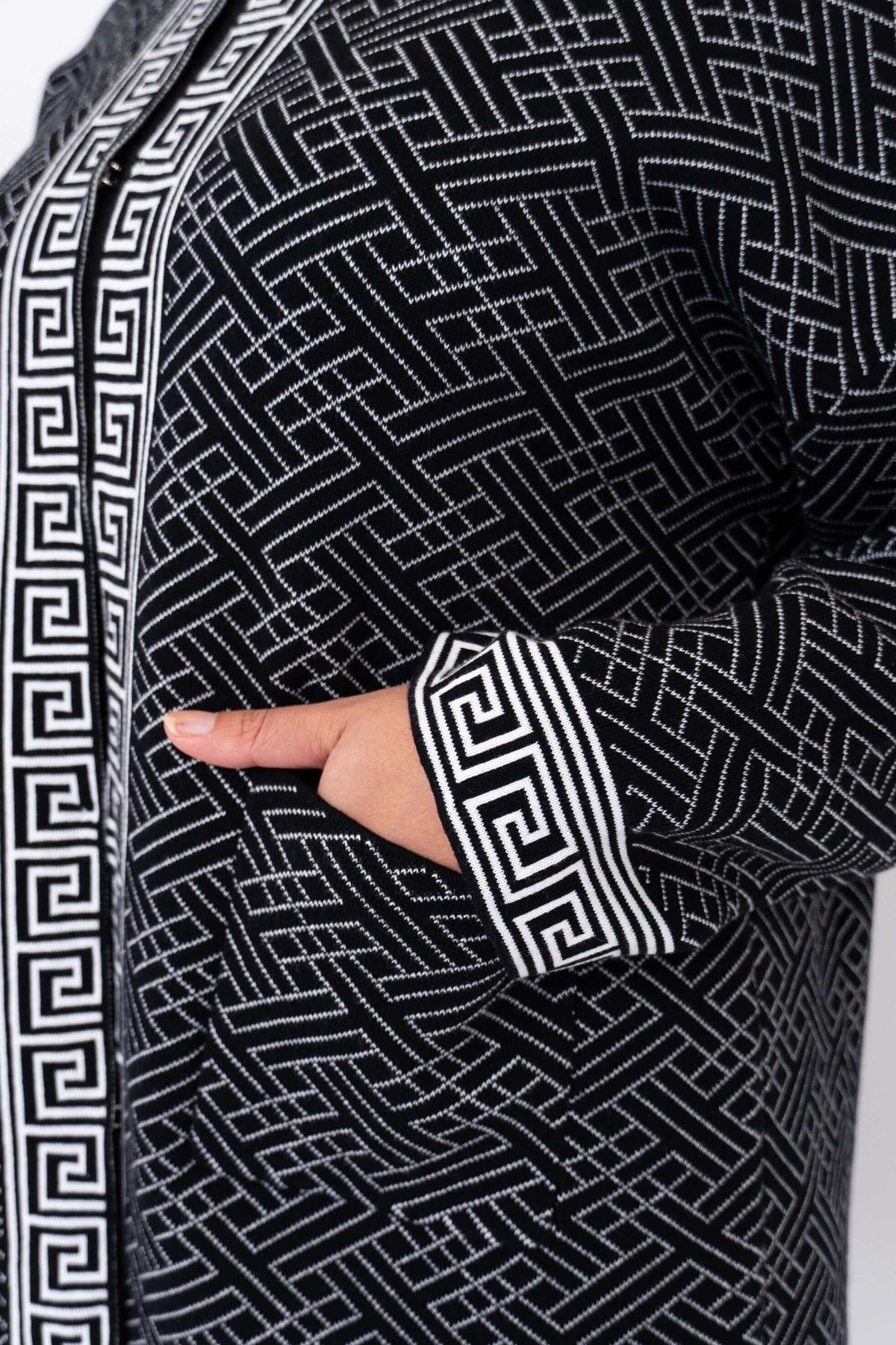 Detail of the front pocket and sleeve cuff with geometric pattern on a black cardigan